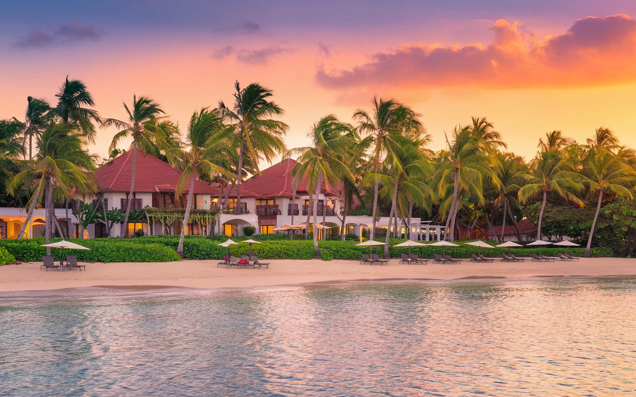 A serene beach at sunset, with a luxurious adults-only resort nestled among palm trees and a sparkling ocean backdrop in Punta Cana