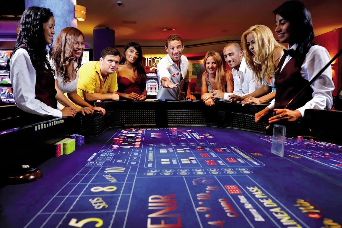 People are shooting dice around a Craps table in the casino at Bahia Principe Fantasia in Punta Cana.