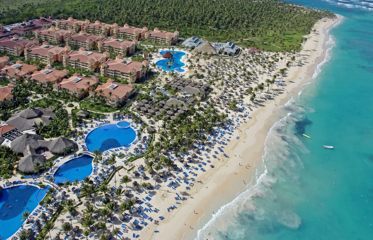 Aerial view of Punta Cana all-inclusive resorts nestled along the white sandy beaches, with palm trees and turquoise waters stretching into the distance