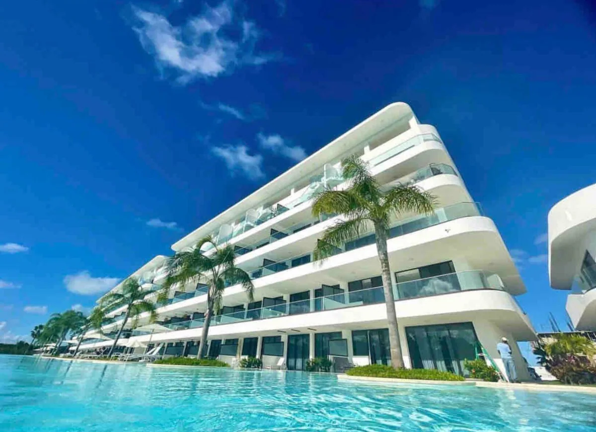 Condo with pool in Punta Cana with palm trees lining the front.