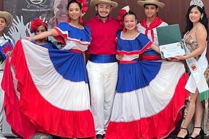 Traditional dancers in the Dominican Republic wearing colorful, flowing dresses and vibrant costumes. They perform lively merengue or bachata dances, showcasing the country\u2019s rich cultural heritage and festive spirit.