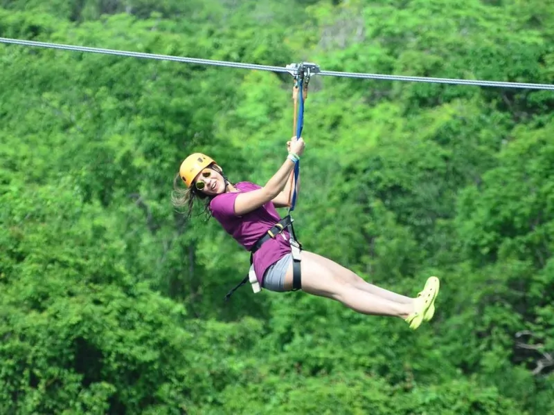 Woman zip-lining over a lush green forest canopy in Punta Cana